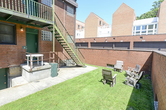 Neville backyard - grassy yard with four wooden lawn chairs surrounded by a brick wall